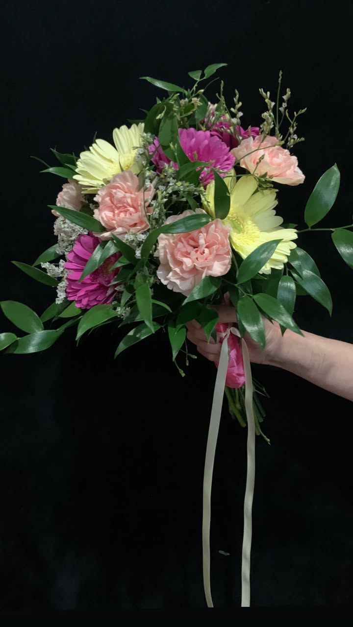 Close-up of a luxurious organic floral arrangement featuring large creamy peonies, wild roses, and dark textured foliage against a soft neutral background